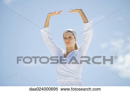 Young woman with arms over head, low angle view View Large Photo Image Stock Photography - Young woman with arms over head, low angle view. Fotosearch