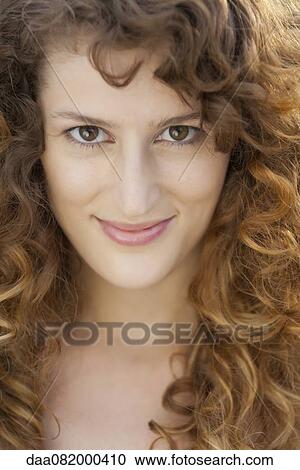 Stock Image - Young woman with curly hair, portrait. Fotosearch