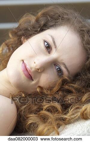 Young woman with curly hair, smiling at camera View Large Photo Image Stock Image - Young woman with curly hair, smiling at camera. Fotosearch