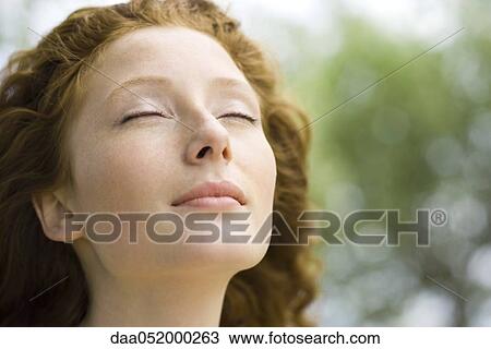 Stock Image - Young woman with eyes closed and serene expression on face, portrait. Fotosearch
