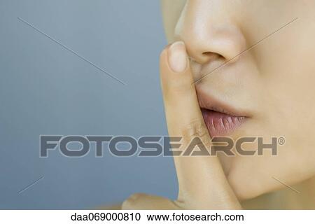 Young woman with finger held to lips, cropped View Large Photo Image Stock Image - Young woman with finger held to lips, cropped. Fotosearch