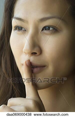Young woman with finger on lips View Large Photo Image Stock Photo - Young woman with finger on lips. Fotosearch