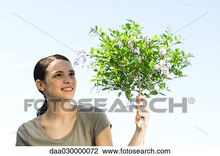 Stock Image - Young woman with flowering topiary tree. Fotosearch