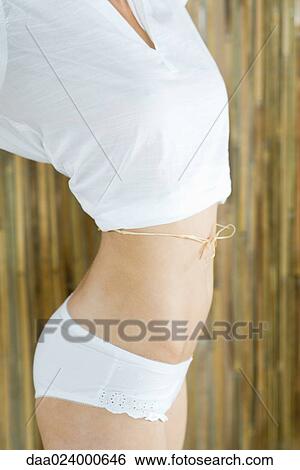 Young woman with piece of raffia tied around waist, cropped View Large Photo Image Stock Photograph - Young woman with piece of raffia tied around waist, cropped. Fotosearch