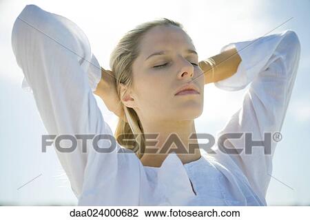 Young woman with sky in background, pushing hair back, eyes closed, low angle view View Large Photo Image Stock Image - Young woman with sky in background, pushing hair back, eyes closed, low angle view. Fotosearch