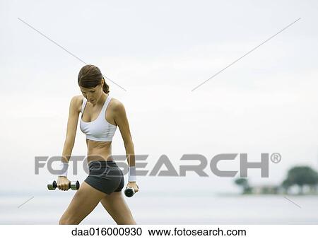 Young woman working out with weights by lakeside View Large Photo Image Stock Image - Young woman working out with weights by lakeside. Fotosearch