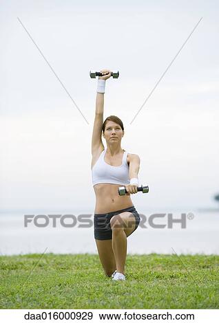 Young woman working out with weights by lakeside View Large Photo Image Stock Photo - Young woman working out with weights by lakeside. Fotosearch