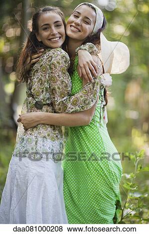 Stock Photo - Young women embracing outdoors, portrait. Fotosearch