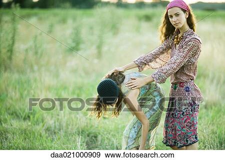 Young women in field, one bending over while the other holds her back View Large Photo Image Stock Photo - Young women in field, one bending over while the other holds her back. Fotosearch