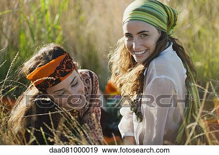 Stock Photo - Young women reclining in grass together. Fotosearch