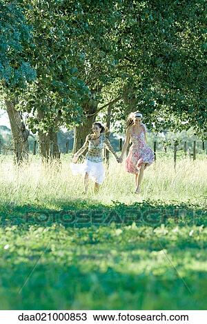 Young women running through field, holding hands View Large Photo Image Stock Image - Young women running through field, holding hands. Fotosearch