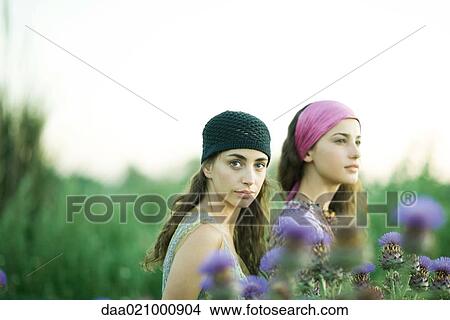 Picture - Young women standing in field, thistle in foreground. Fotosearch