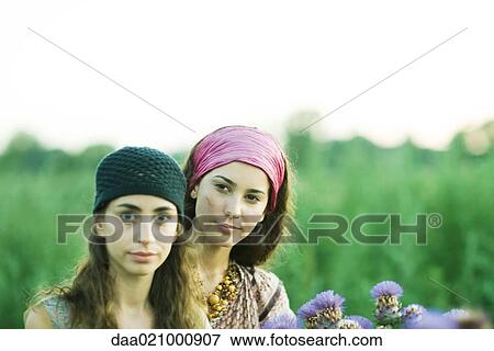 Stock Photo - Young women standing in field, thistle in foreground. Fotosearch