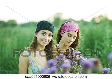 Stock Photograph - Young women standing in field, thistle in foreground. Fotosearch