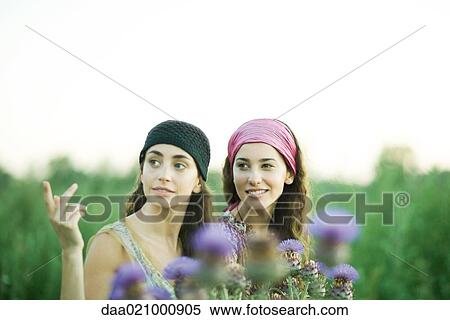 Stock Photography - Young women standing in field, thistle in foreground. Fotosearch