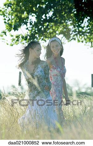 Young women walking through field View Large Photo Image Stock Image - Young women walking through field. Fotosearch