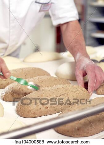 Stock Photo - Baker scoring bread dough, cropped. Fotosearch