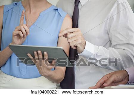 Stock Image - Business colleagues working together with digital tablet, cropped. Fotosearch