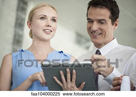 Stock Photography - Business professionals looking at digital tablet together and laughing. Fotosearch
