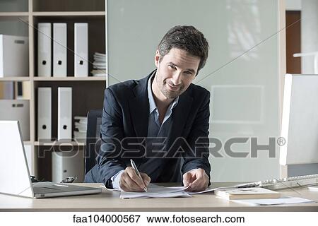 Businessman completing paperwork View Large Photo Image Stock Photo - Businessman completing paperwork. Fotosearch