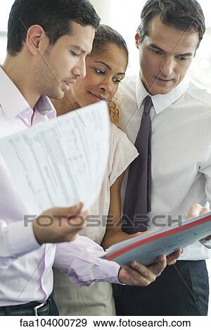 Businessman discussing documents with colleagues View Large Photo Image Stock Photo - Businessman discussing documents with colleagues. Fotosearch