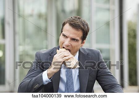 Businessman eating sandwich outdoors View Large Photo Image Stock Photo - Businessman eating sandwich outdoors. Fotosearch