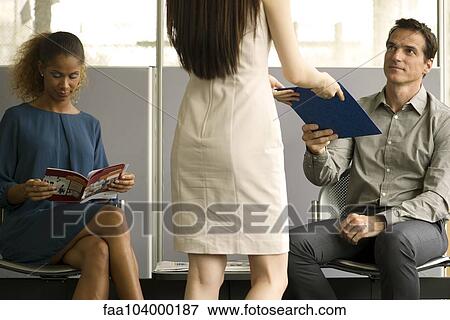 Businessman handing paperwork to woman in waiting room View Large Photo Image Stock Photo - Businessman handing paperwork to woman in waiting room. Fotosearch