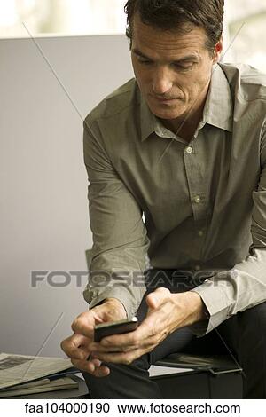 Stock Image - Businessman looking at smartphone. Fotosearch