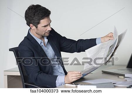 Businessman reading newspaper in office View Large Photo Image Stock Image - Businessman reading newspaper in office. Fotosearch