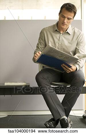 Picture - Businessman reading newspaper in waiting room. Fotosearch