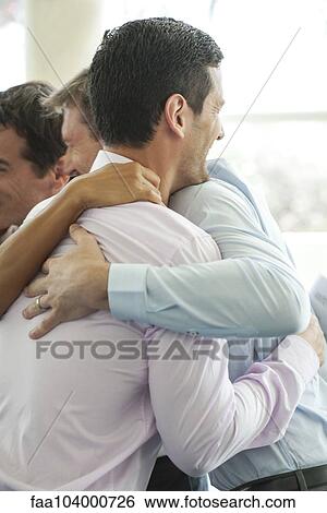 Stock Photograph - Businessmen hugging in celebration over good news. Fotosearch