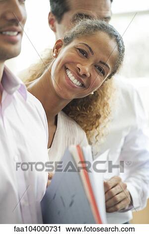 Stock Image - Businesswoman leaning out between two colleagues, smiling cheerfully. Fotosearch