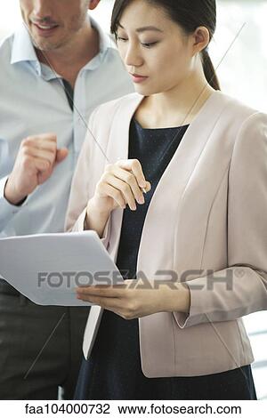 Stock Image - Businesswoman reviewing document. Fotosearch