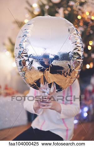 Stock Photography - Child with face obscured by silver balloon. Fotosearch