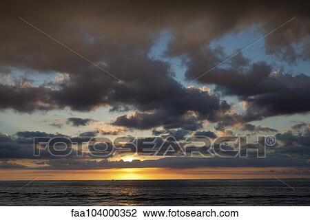 Stock Image - Cloudy sky over sea during sunset. Fotosearch