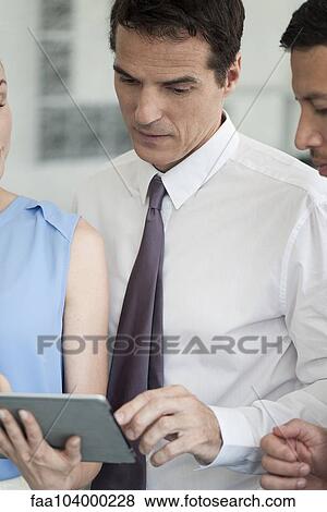 Stock Photo - Colleagues collaborating using digital tablet. Fotosearch