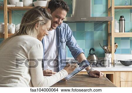 Picture - Couple using digital tablet at home. Fotosearch