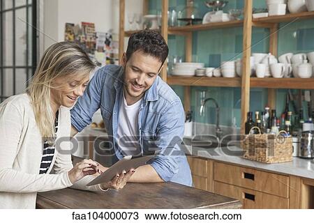 Couple using digital tablet in kitchen View Large Photo Image Stock Image - Couple using digital tablet in kitchen. Fotosearch