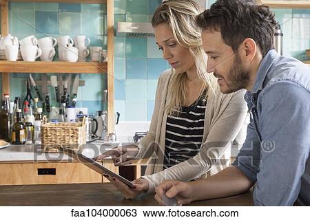 Stock Image - Couple using digital tablet to shop online. Fotosearch