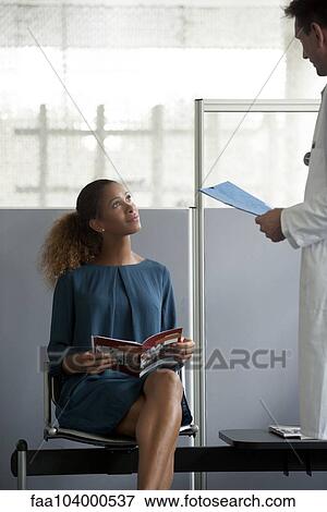 Stock Photo - Doctor chatting with patient in waiting room. Fotosearch