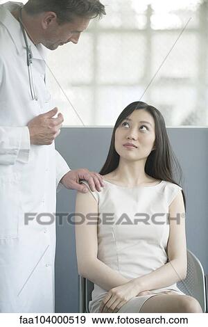 Stock Photo - Doctor speaking with patient in waiting room. Fotosearch