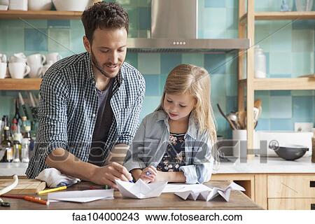 Stock Image - Father and young daughter drawing in kitchen. Fotosearch