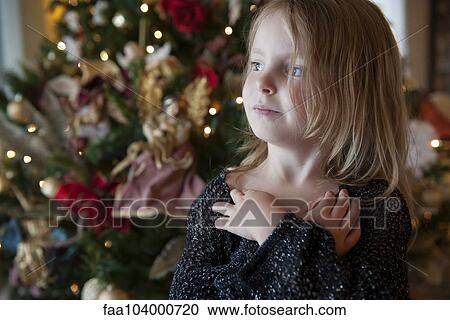 Girl daydreaming with Christmas tree in background View Large Photo Image Stock Image - Girl daydreaming with Christmas tree in background. Fotosearch