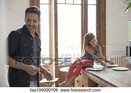 Girl helping father set table for family meal View Large Photo Image Stock Photo - Girl helping father set table for family meal. Fotosearch