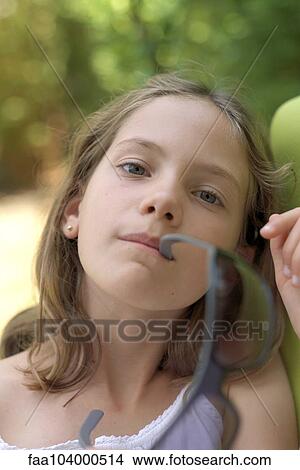Girl holding sunglasses in her mouth, portrait View Large Photo Image Picture - Girl holding sunglasses in her mouth, portrait. Fotosearch