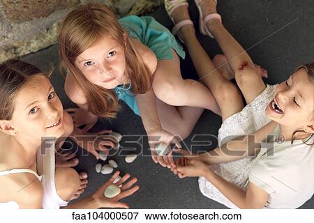 Girls sitting together playing with pebbles View Large Photo Image Stock Photo - Girls sitting together playing with pebbles. Fotosearch