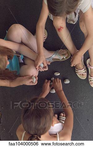 Girls sitting together playing with pebbles View Large Photo Image Stock Photograph - Girls sitting together playing with pebbles. Fotosearch