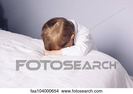 Picture - Little boy resting head on bed. Fotosearch