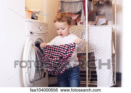 Stock Photograph - Little boy taking clothes out of dryer. Fotosearch