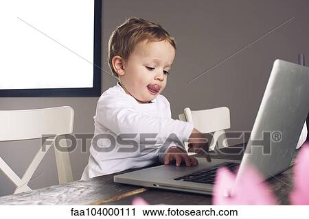 Stock Image - Little boy using laptop computer. Fotosearch